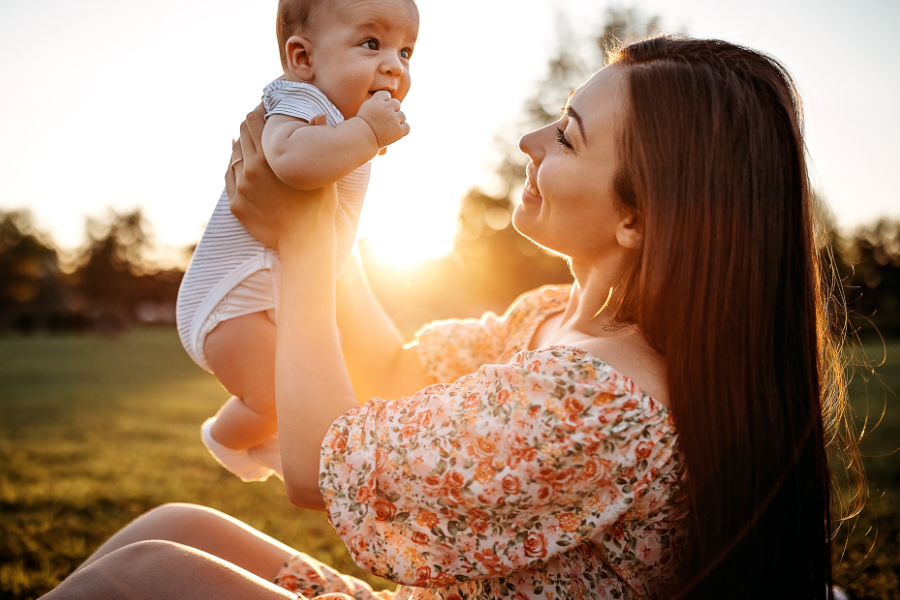 Woman outside with her new born baby with the sunrise in the background
