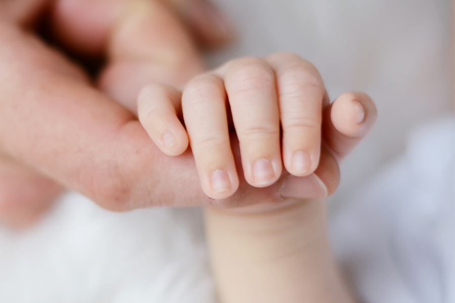 New born baby hand holding an adult finger 