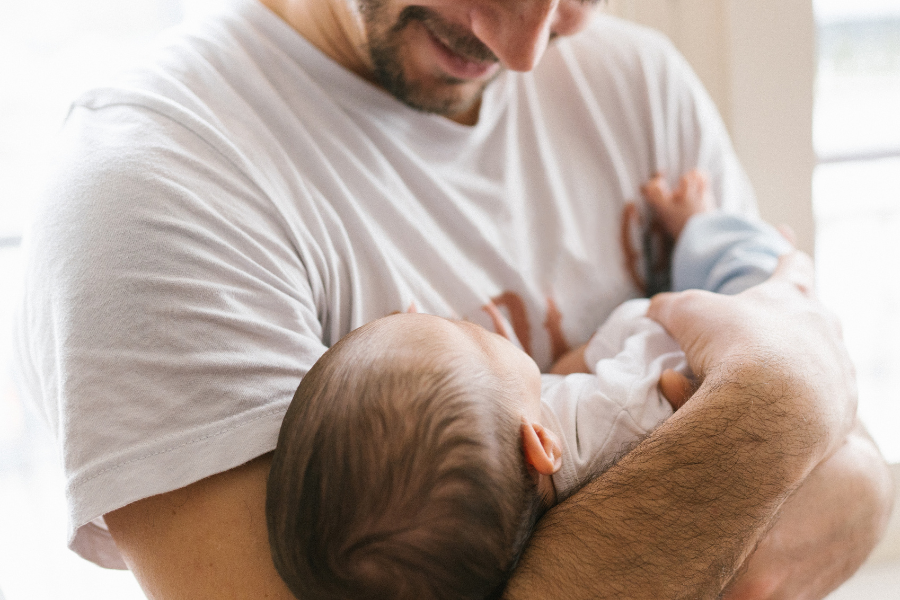 Man holding new born baby in arms in doors